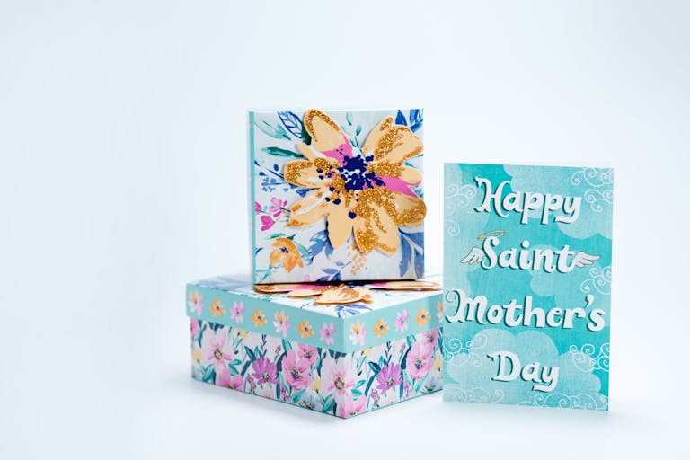 Elegant floral gift boxes and card celebrating Mother's Day with vibrant colors and text.